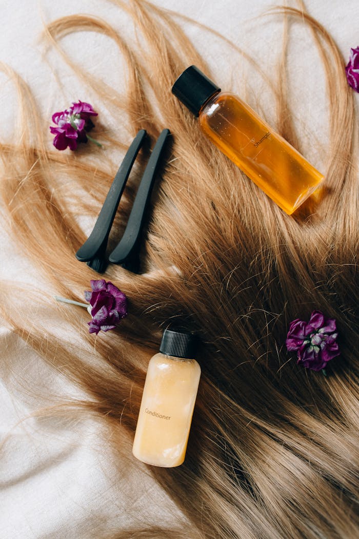 Aesthetic flatlay of hair care items and flowers against a soft background.